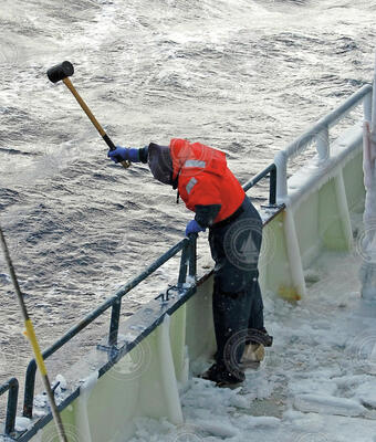 R/V Knorr crew member knocking ice of the ship's hull in the North Atlantic.