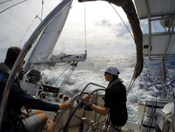 Coral reef researcher Tom DeCarlo (right) piloting a sailboat in the Caribbean.