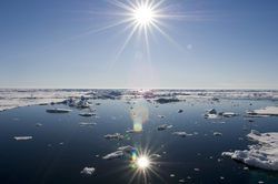 Arctic sunburst over ice and water.