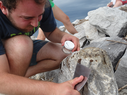 Bryan James collecting an oil spill sample off the jetty rocks.
