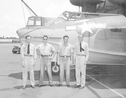 Group of four men in front of PBY aircraft.