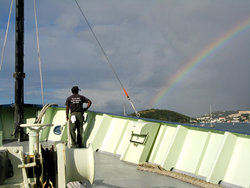 Clindor Cacho admiring a rainbow off the bow of Oceanus.