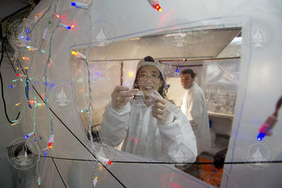 Phoebe Lam and Dan Ohnemus working inside a plastic bubble lab.