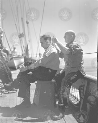 Otto Solberg giving Capt Adrian Lane a haircut on deck.