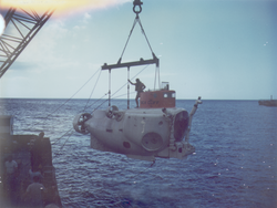 Sea Cliff suspended over the water by a crane, man standing on top