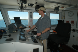 Ken Houtler, captain of Tioga, at the helm.