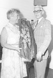 Mary Sears holding roses, standing with Paul Fye