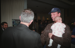 Bob Ballard, holding Emily Rose, shaking hands with guests.