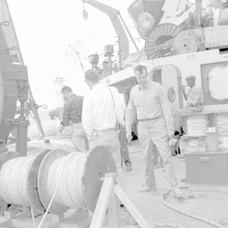 Alfred C. John (with pipe) and group working on deck of Chain, spools in front