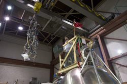 Chris Lathan guiding a wiring harness into Alvin sphere for installation.