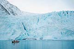 Researchers in small boat exploring the face of a glacier in Aialik Bay, Alaska.