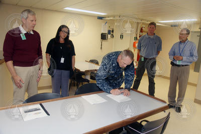 U.S. Navy Commander William Fallier signing the possession transfer paperwork.