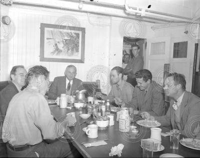 People gathered at the mess table in the Wardroom