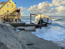 A coastal home falls into the ocean due to n'oreaster erosion.