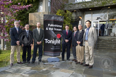 Colloquium speakers with event banner in front of Redfield Auditorium.