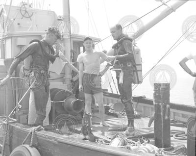 Three men on deck of the Asterias, two divers