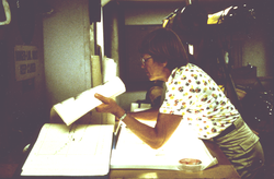 Betty Bunce on the Atlantis II looking at bathy-track chart atlas.