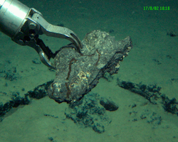 Manipulator arm collecting a rock during Alvin dive 3821.