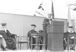 Paul M. Fye in [cap and] gown speaking at podium