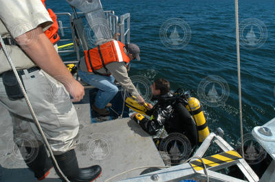Captain Ken Houtler assists diver Brennan Phillips on Tioga.