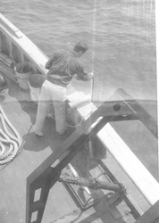 Unidentified man works with hoses on the deck of the Bear