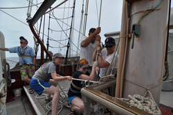 Students raising the sail on the Cramer during the JP summer cruise.