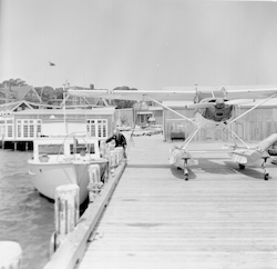 Helio courier on end of Dyers dock, hangar in background.
