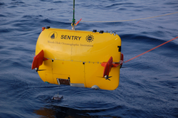 AUV Sentry suspended over the water during deployment operations.