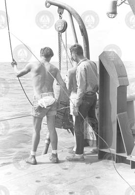 Three men on deck with coring instrument over the side