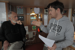 Writer Dallas Murphy and Postdoc Ben Harden talking on the bridge of R/V Lance.