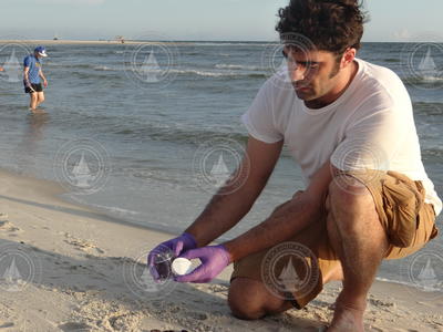 Ferdinand Oberle collecting an oil sample from the beach. Freiberg behind.