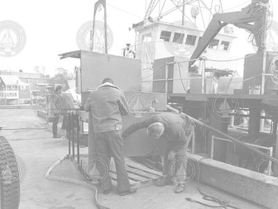 Three men on dock working with equipment, Lulu at dock