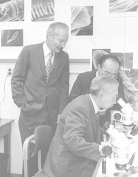 Howard Sanders and Susumu Honjo with Emperor Hirohito at microscope.