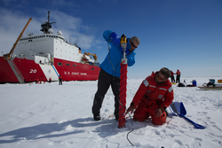 Ken Golden and Chris Polashenski drilling out an ice core in front of Healy.