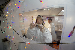 Phoebe Lam and Dan Ohnemus working inside a plastic bubble lab.