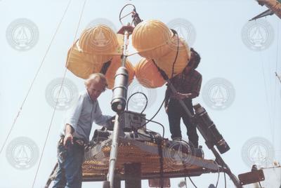 Two unidentified men working with buoy and instruments