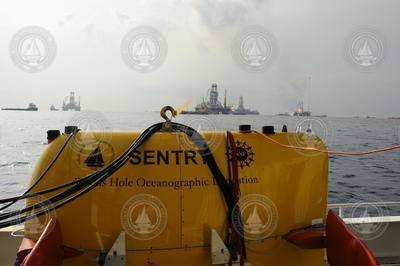AUV Sentry on deck of Endeavor with oil spill activities in background.