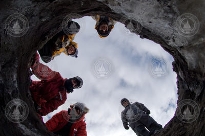 Researcher peering down into a hole in Antarctica.