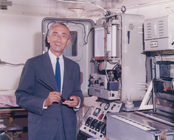 Jacques Cousteau standing in front of equipment