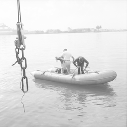 Three men on a boat diving.