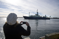 A spectator taking photos of R/V Knorr departing Woods Hole.