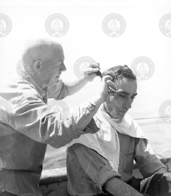 Otto Solberg cutting Captain Lane's hair on deck
