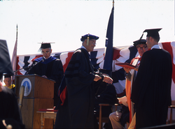 Graduates receiving diplomas and congratulations.