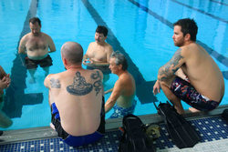 Captain A.D. Colburn (top center) and crew working on exercises in a pool.
