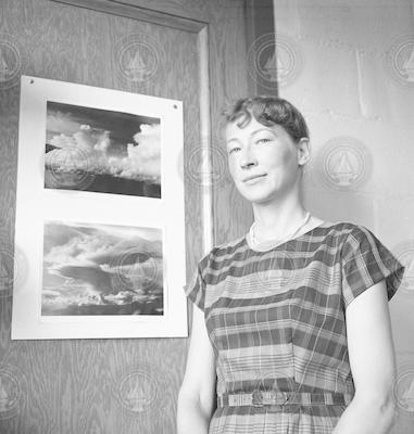 Meteorologist Joanne Malkus standing next to a photo featuring clouds.