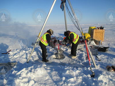 Kris Newhall and John Kemp using an auger to drill an ice hole for an ITP installation.