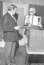 Paul Fye showing album of photos to Claude Ronne