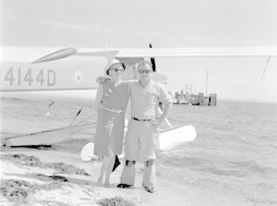 Robert Weeks and an unidentified person on beach next to Helio courier.