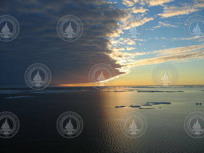 Ice chunks in the arctic ocean under a dramatic cloud covered sky.