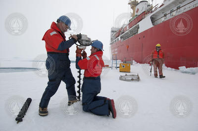 John Kemp and Kris Newhall drill through the ice.